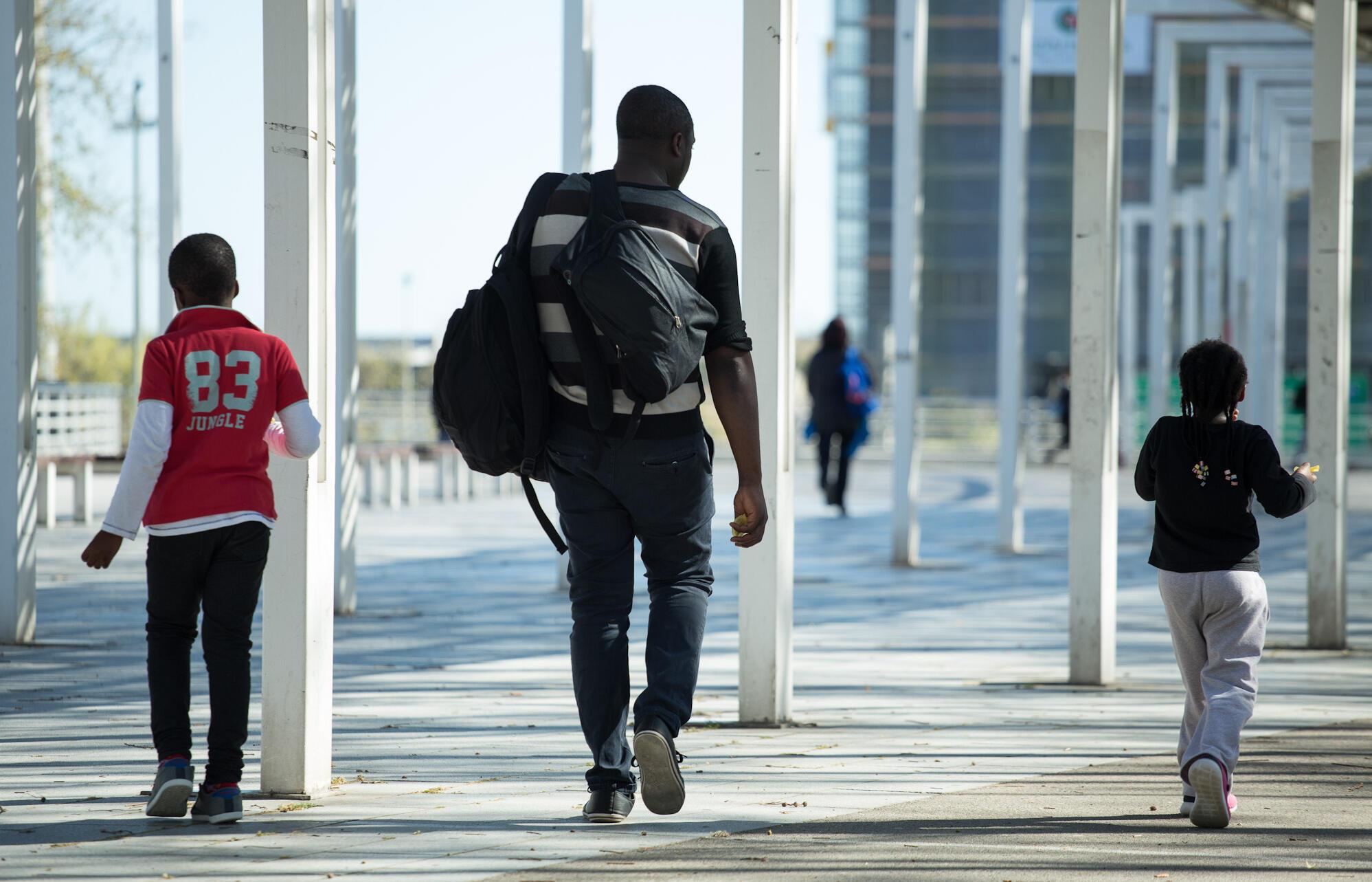 Imatge d'un jove i infants d'origen migrat caminant