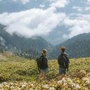 Imatge d'una noia i un noi a la muntanya d'esquenes observant el paisatge