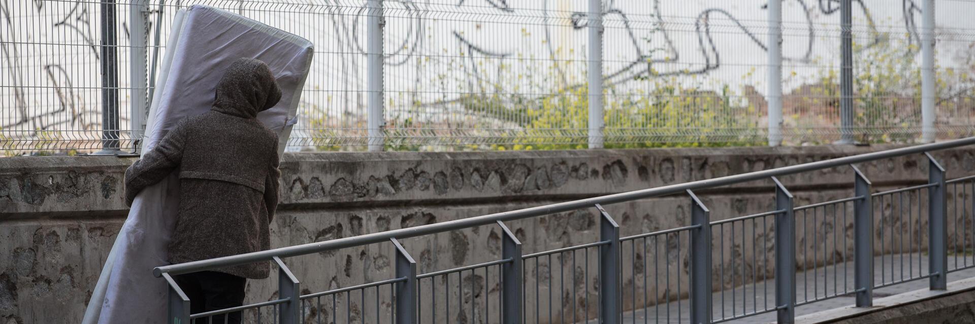 Imatge d'una persona transportant un matalàs al carrer