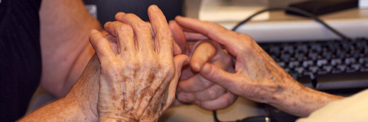 Imatge d'unes mans d'una persona gran i una altra persona en gest de cura