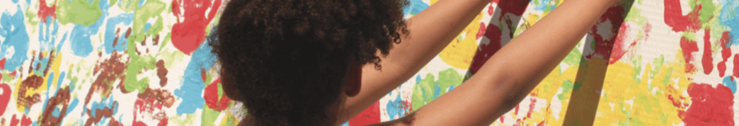 Imatge infant deixant l'empremta de la seva mà amb pintura en un mural