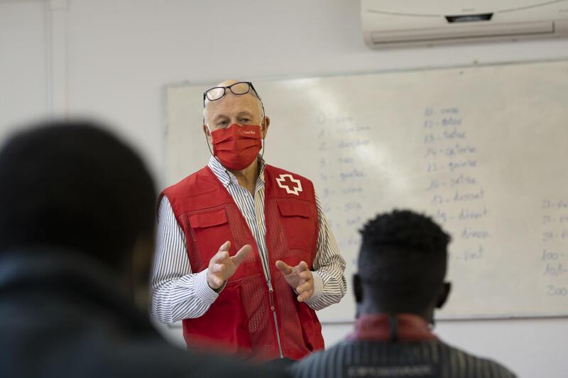 Persona de Creu Roja acompanyant persones refugiades en una aula