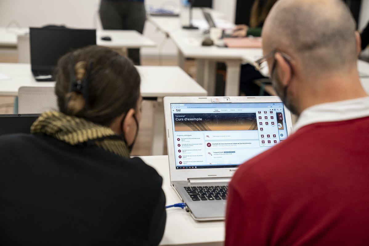 Un parell d'alumnes del taller digital sobre digitalització democràtica de l'educació consulten plegats un portàtil 