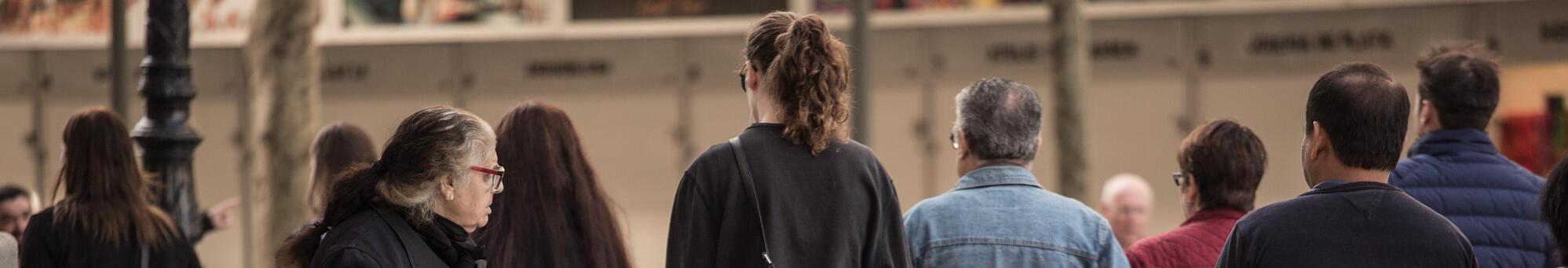 Fotografia persona demanant almoina al carrer, i altres persones caminant