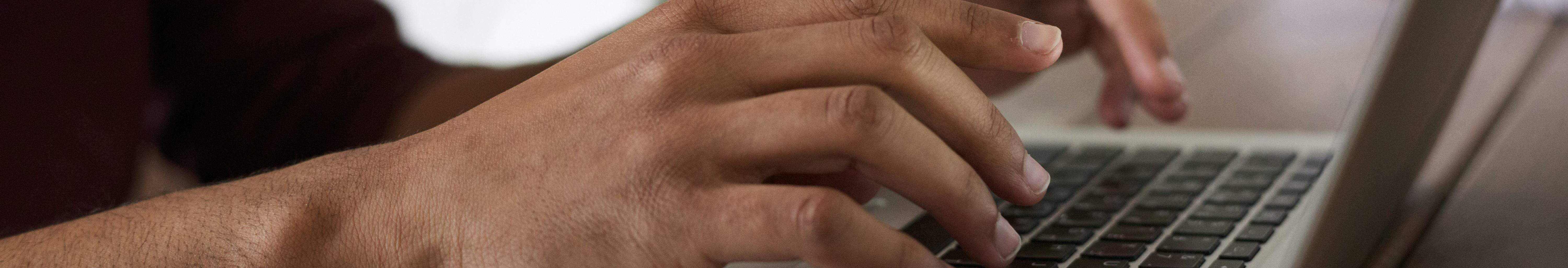 Imatge d'un ordinador i una persona treballant-hi