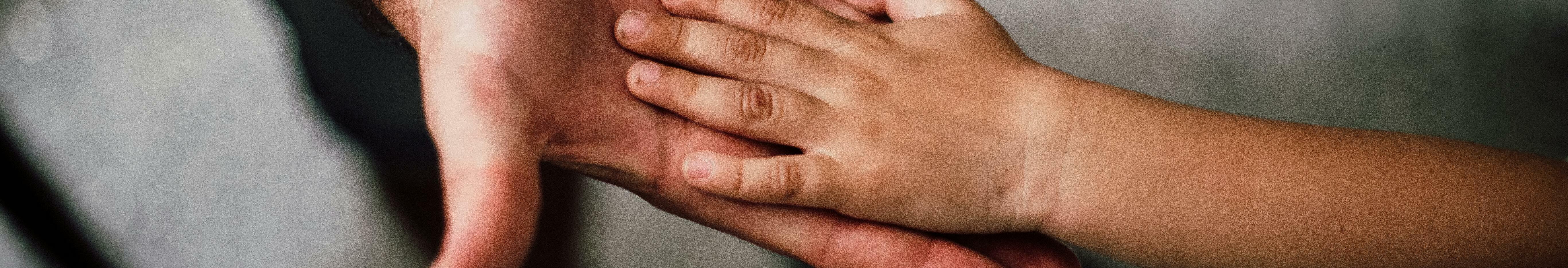 Un adult i un infant donant-se la mà.