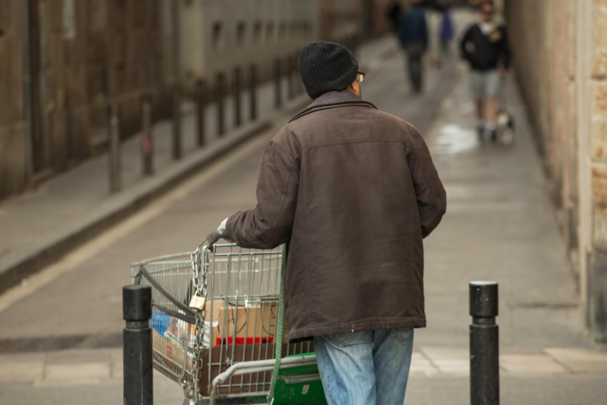 Imatge persona sense llar amb un carretó de supermercat