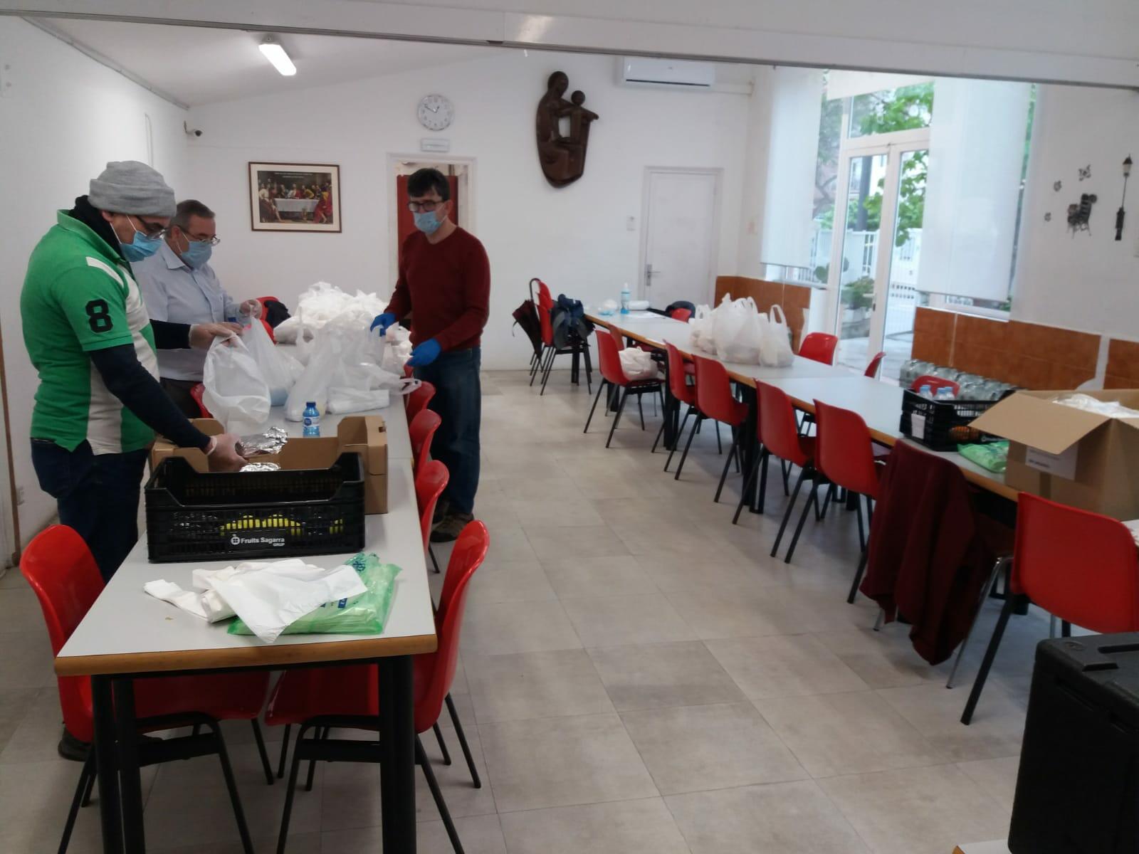 Voluntaris de Càritas disposant aliments en un menjador social de Sany Cebrià.