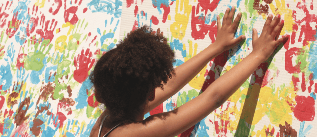 Imatge infant deixant la seva empremta de mà amb pintura en un mural