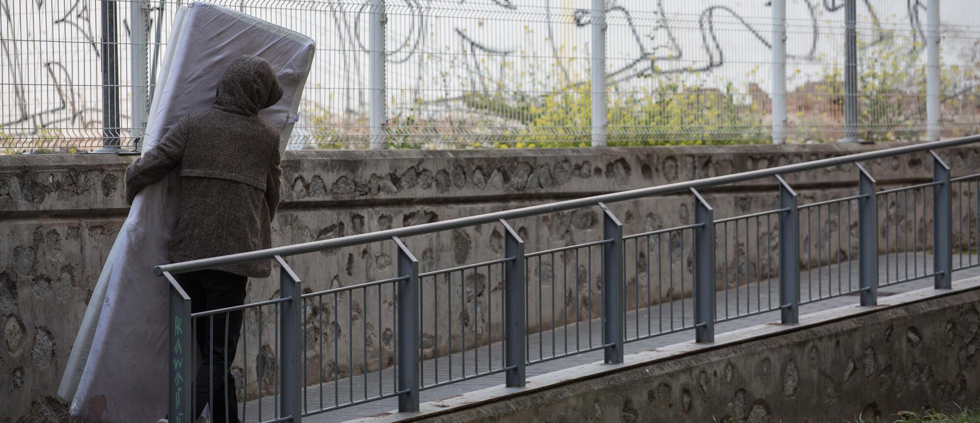 Imatge d'una persona transportant un matalàs al carrer