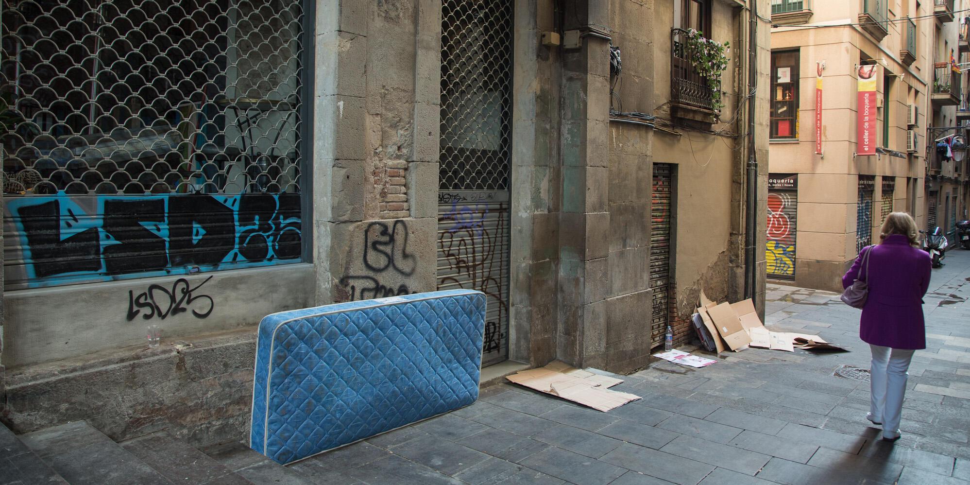 Imatge d'un matalàs i cartrons al carrer de persones sense llar